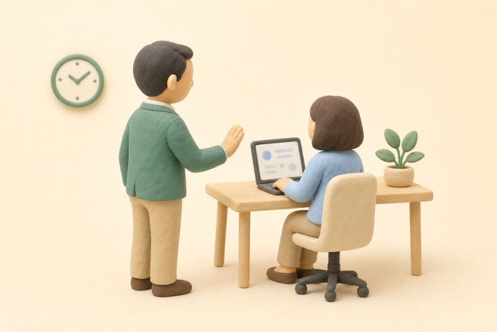 上司が、パソコンで答えている部下に、少し離れた所から穏やかに声をかけている様子のイメージ